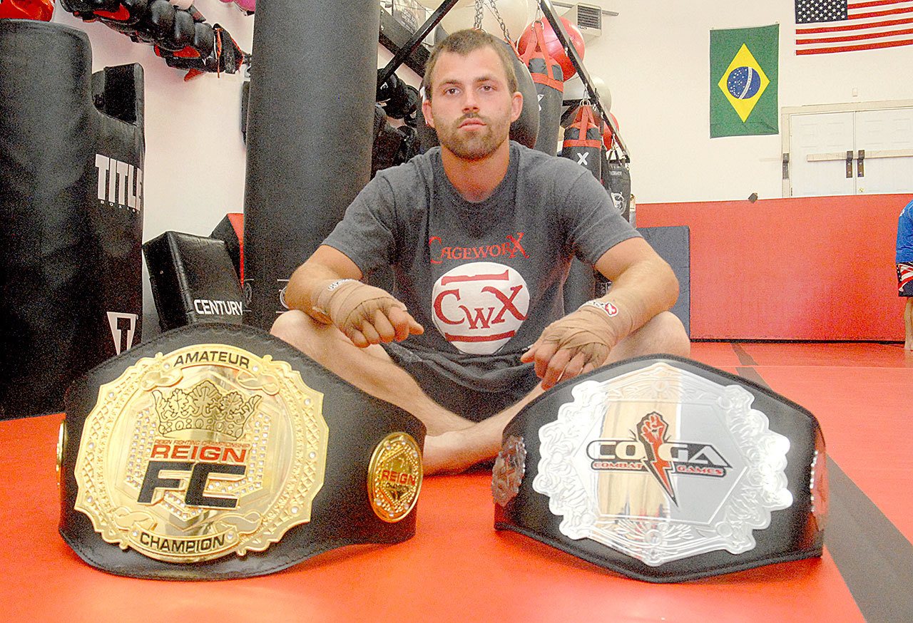 Keith Thorpe/Peninsula Daily News Port Angeles’ Jacob Goudie displays his Reign FC and Combat Games mixed martial arts title belts during a break from training at CageworX Mixed Martial Arts.