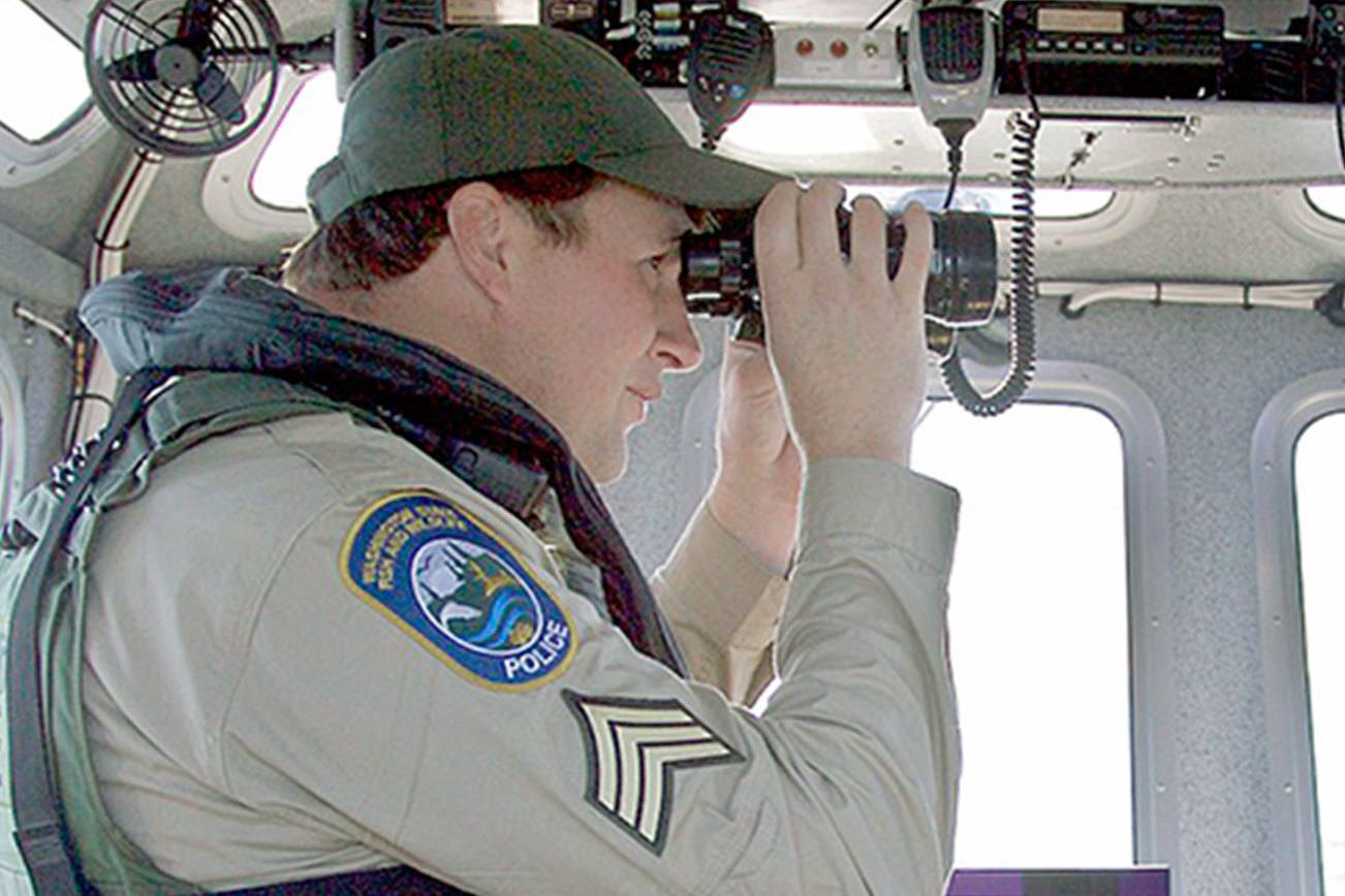 Steve Mullensky/for Peninsula Daily News                                Sgt. Kit Rosenberger of the state Department of Fish and Wildlife Police, scans the horizon whileOfficer Bryan Davidson pilots during a recent patrol of Marine Area 9 in Admiralty Inlet and theStrait of Juan de Fuca off Port Townsend.