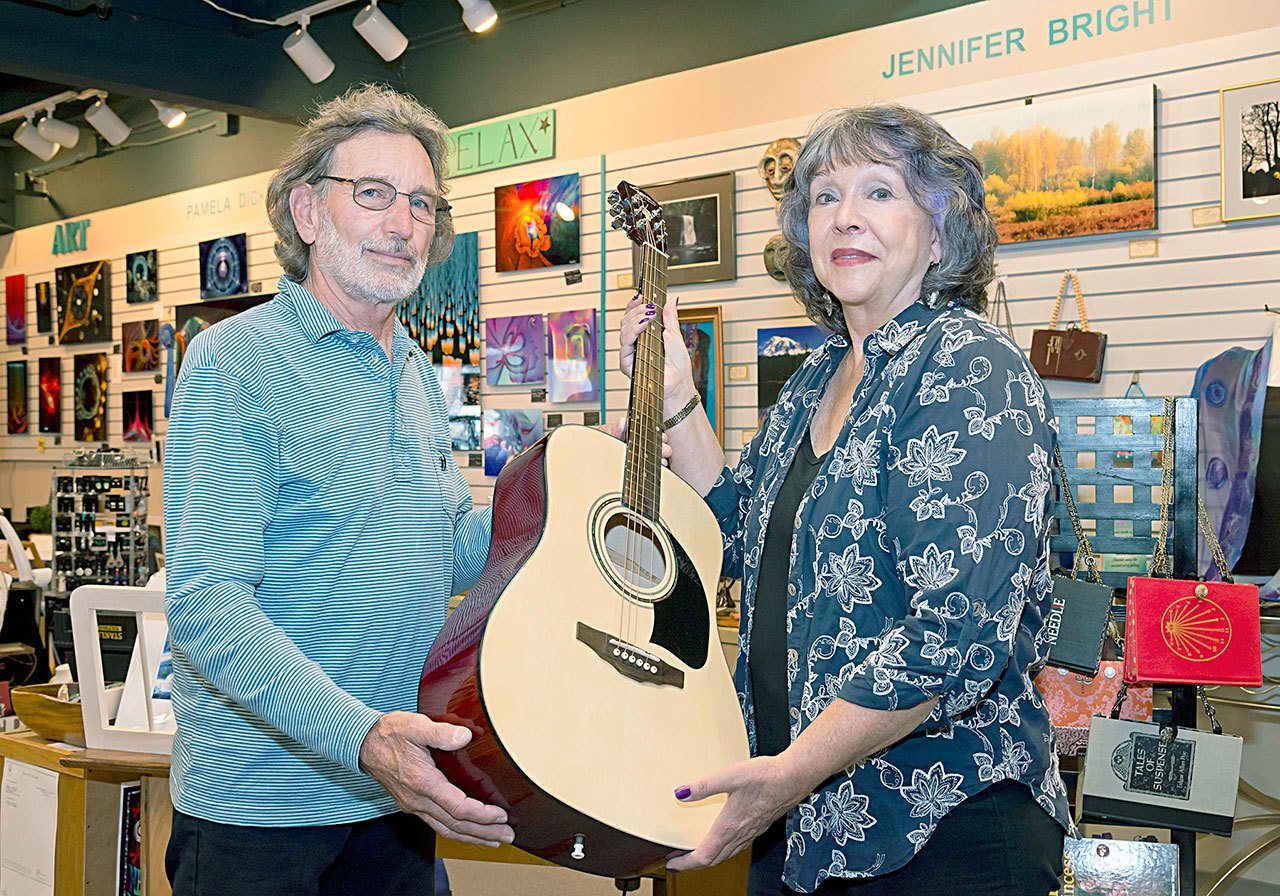 Jennifer Bright, Juan de Fuca Foundation board member and guitar auction committee chair, accepts a guitar donation from Doug Parent. (JFFA)