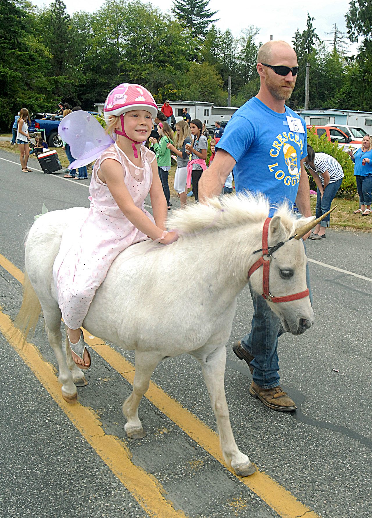 Darica Bertelson, 6, of Joyce rides her unicorn-costumed horse, Precious Pickles, led by her father, Darrin Bartelson, as they take part in the Joyce Daze grand parade. (Keith Thorpe/Peninsula Daily News)