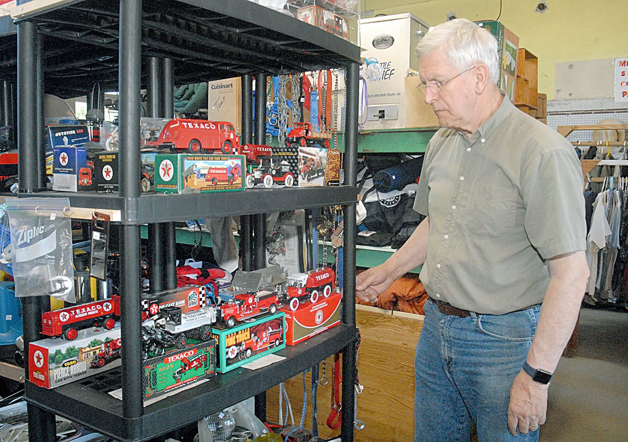 Clallam County Historical Society volunteer Patrick Noonan of Port Angeles looks at part of a collection of commemorative metal piggy banks in the guise of model cars, trucks and airplanes that will be up for grabs at the society’s annual garage sale fundraiser. (Keith Thorpe/Peninsula Daily News)