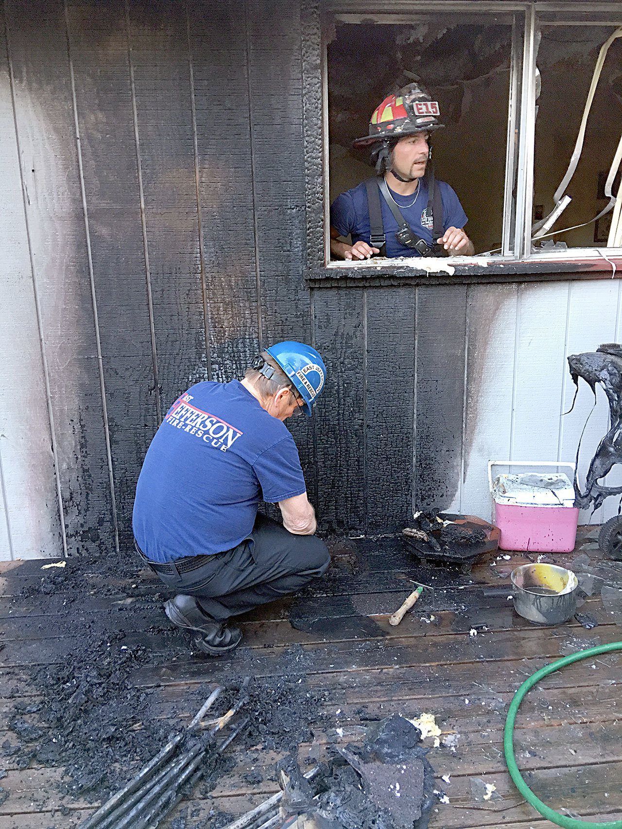 East Jefferson Fire-Rescue Assistant Chief Wayne Kier examines evidence while Lt. Steve Grimm looks on from inside the house. (East Jefferson Fire-Rescue)