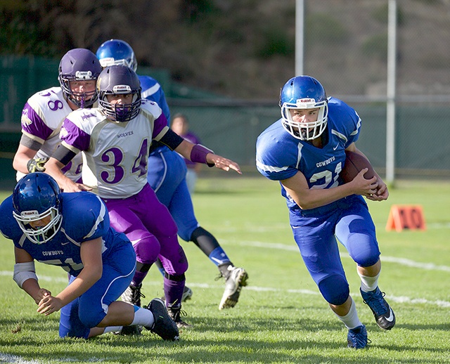 Steve Mullensky/for Peninsula Daily News Chimacum’s Eliajah Avery, right, runs around a block by Aaron Serrato (lower left) during a 2015 game against the Sequim Wolves.