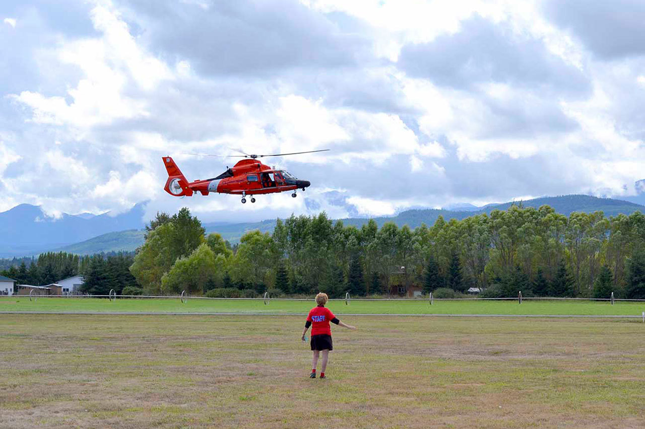 Olympic Peninsula Air Affaire co-organizer Emily Westcott waves to Coast Guardsmen as they do a fly-by at last year’s Air Affaire. Westcott hopes the Coast Guard helicopter stationed on Ediz Hook returns this year for a touch-and-go. (Matthew Nash/Olympic Peninsula News Group)