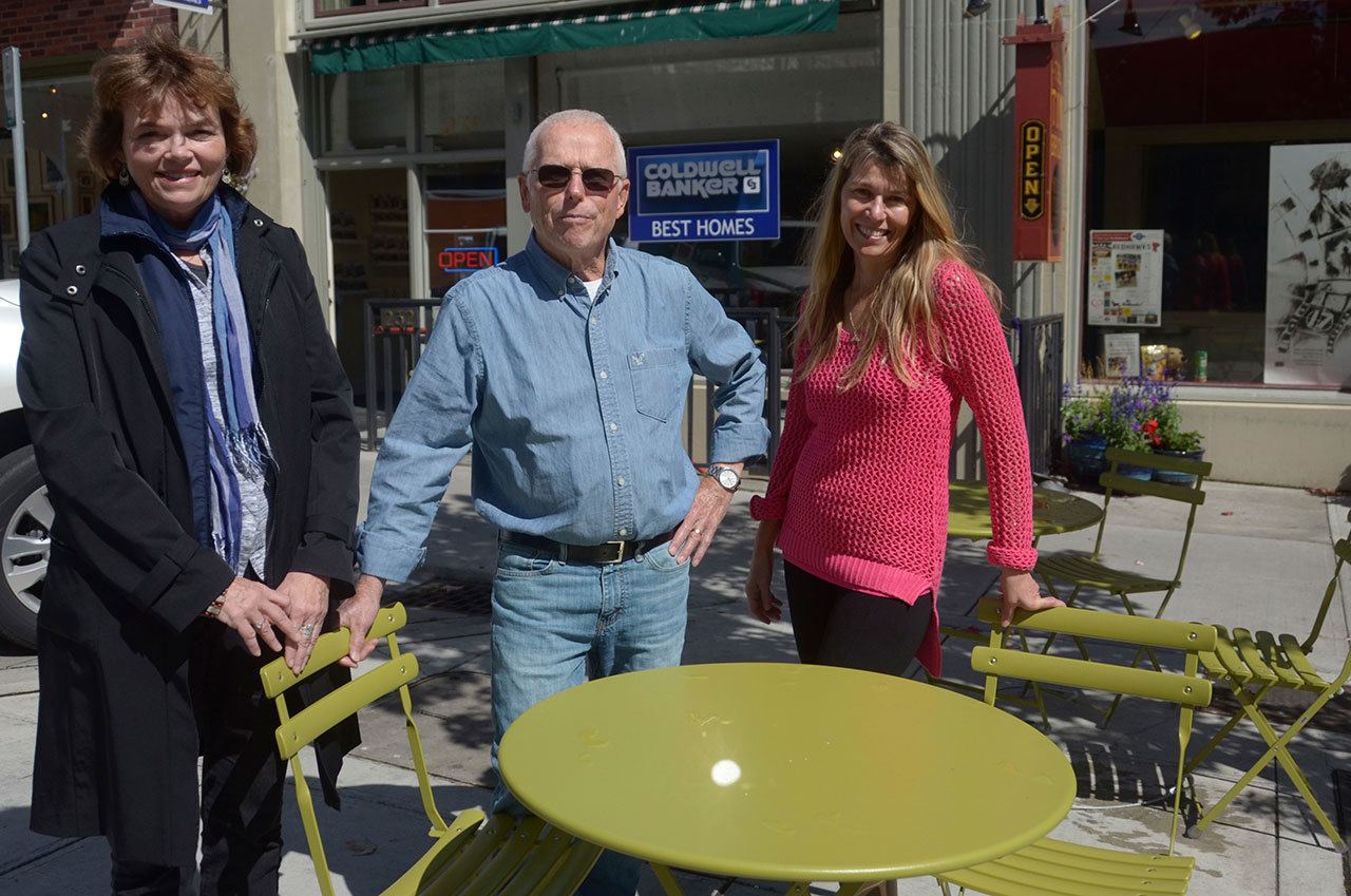 Mari Mullen, left, director of the Port Townsend Main Street Program, stands with Coldwell Broker employees Forrest Aldrich, the designated broker, and Belinda Button, the office manager, in the new seating area on Taylor Street in downtown Port Townsend. (Cydney McFarland/Peninsula Daily News)