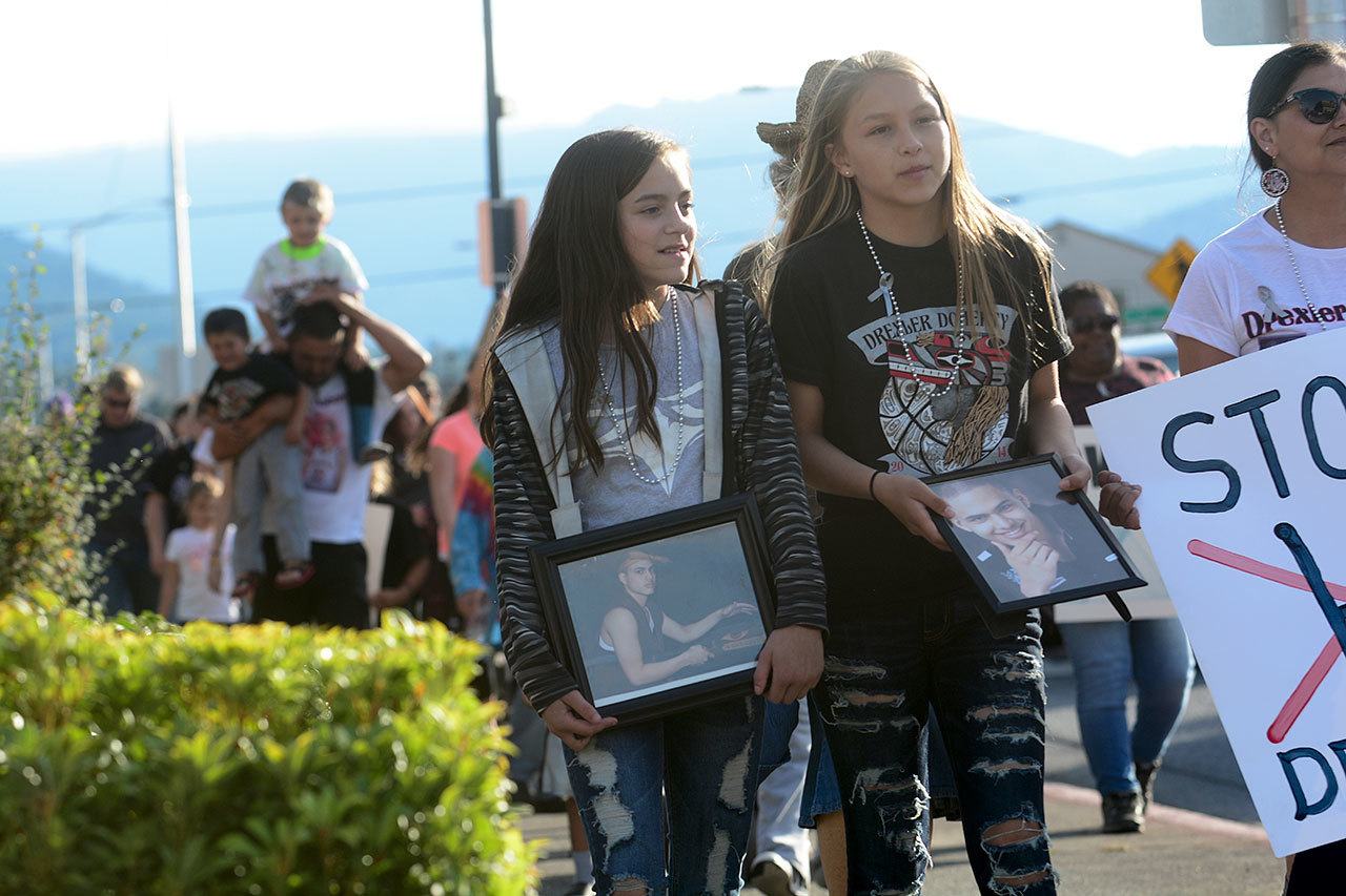 Paris Horejsi, 12, right, and Sonciraye Hottowe, 11, carry photos of Drexler Doherty, Horejsi’s brother, who passed away after an overdose in 2013. (Jesse Major/Peninsula Daily News)