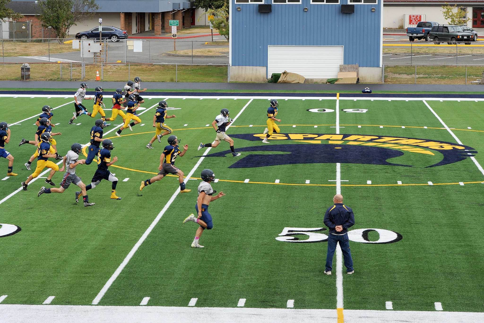 Lonnie Archibald/For Peninsula Daily News Forks assistant coach Jimmy Leppell looks on as players run sprints during the football team’s first practice Tuesday on the new Spartan Stadium FieldTurf playing surface.