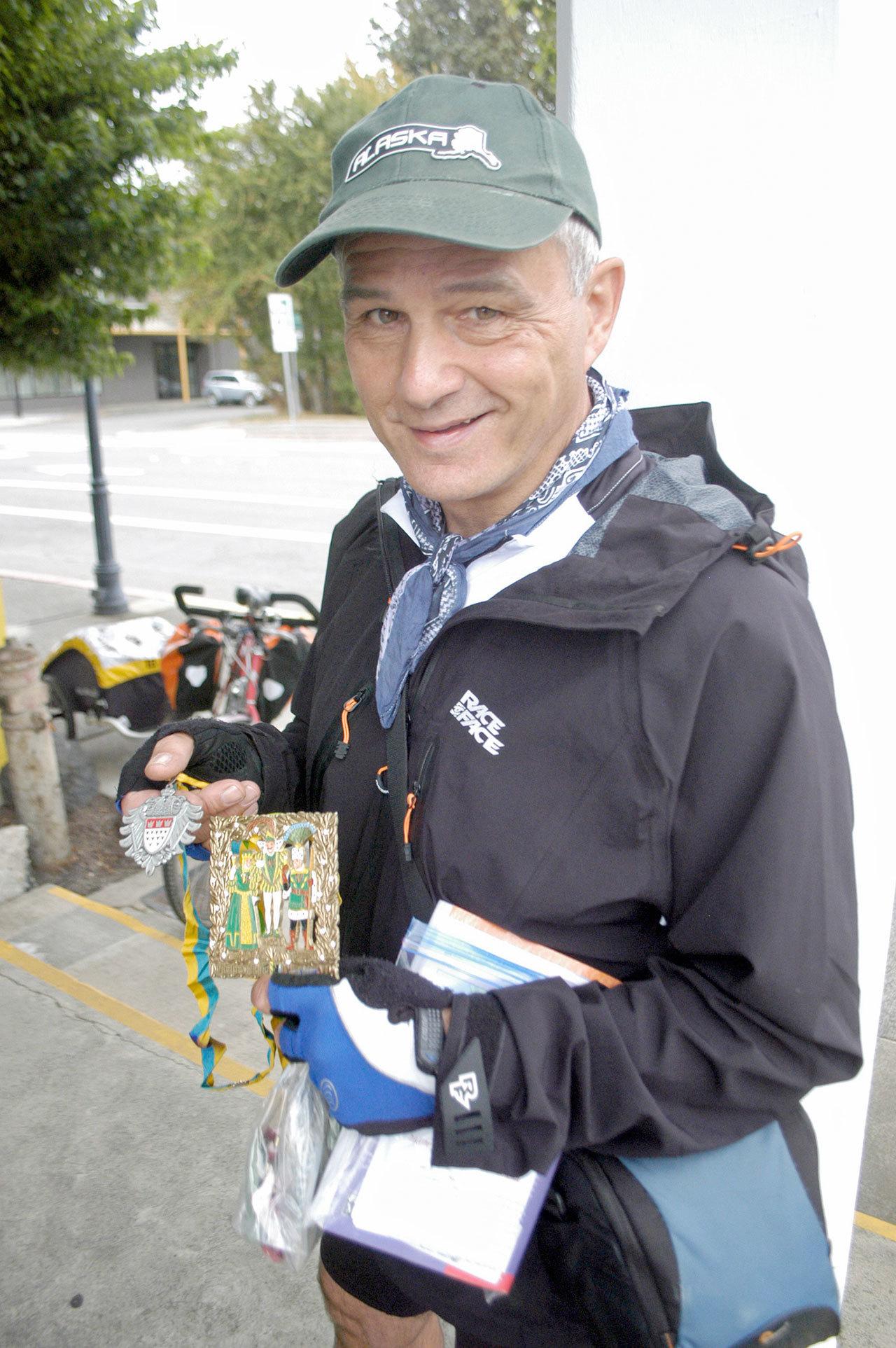 Klaus Luttgen of Germany is riding his bicycle from Vancouver, B.C., to San Francisco this month, giving away carnival medals from his hometown to interesting folks along the way. (Chris McDaniel/Peninsula Daily News)