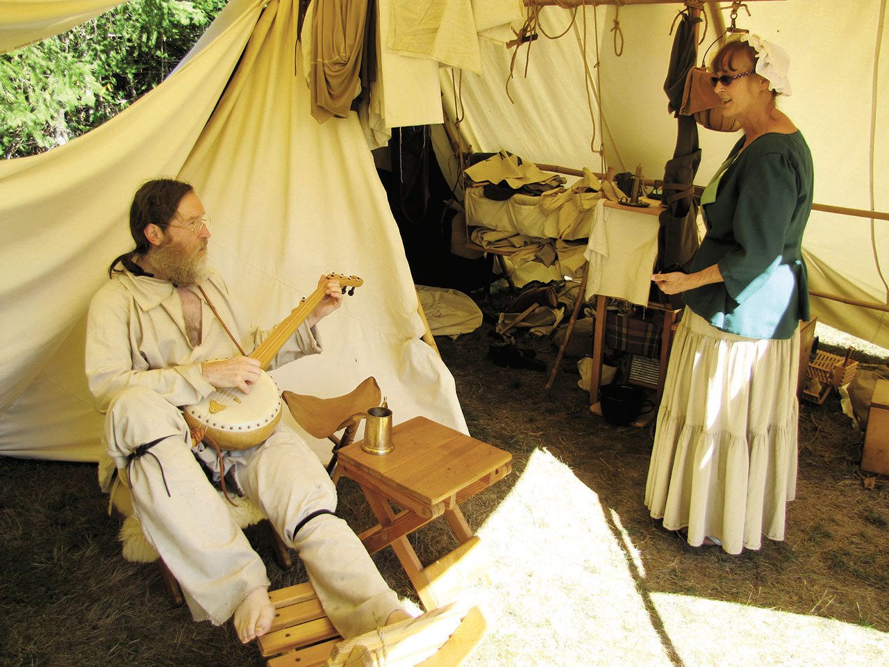 Donna Helgeson of Sedro-Woolley, right, visits with her tent neighbor, Eric J. Sisk of Seattle, at the Green River Mountain Men’s annual rendezvous in 2013. (Peninsula Daily News)