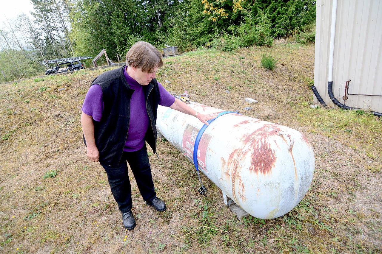 Donna Buck shows how the Joyce Emergency Planning and Preparation group wants residents to secure propane tanks, which would reduce the risk of fire in the event of a catastrophic earthquake. (Jesse Major/Peninsula Daily News)