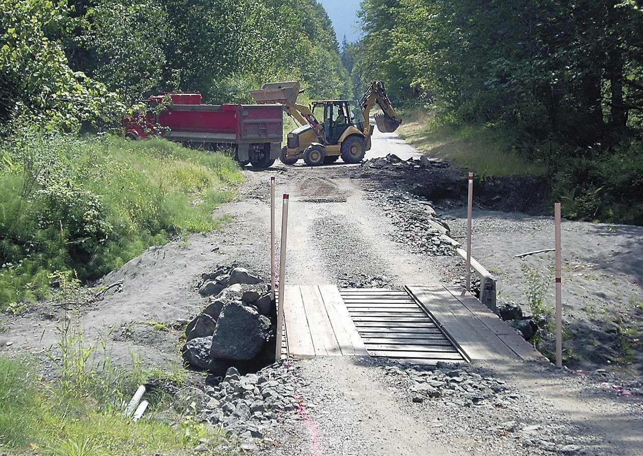 An excavator loads pieces of old roadway into a dump truck at the site of a washout on Olympic Hot Springs Road in the Elwha Valley of Olympic National Park in July. (Keith Thorpe/Peninsula Daily News)