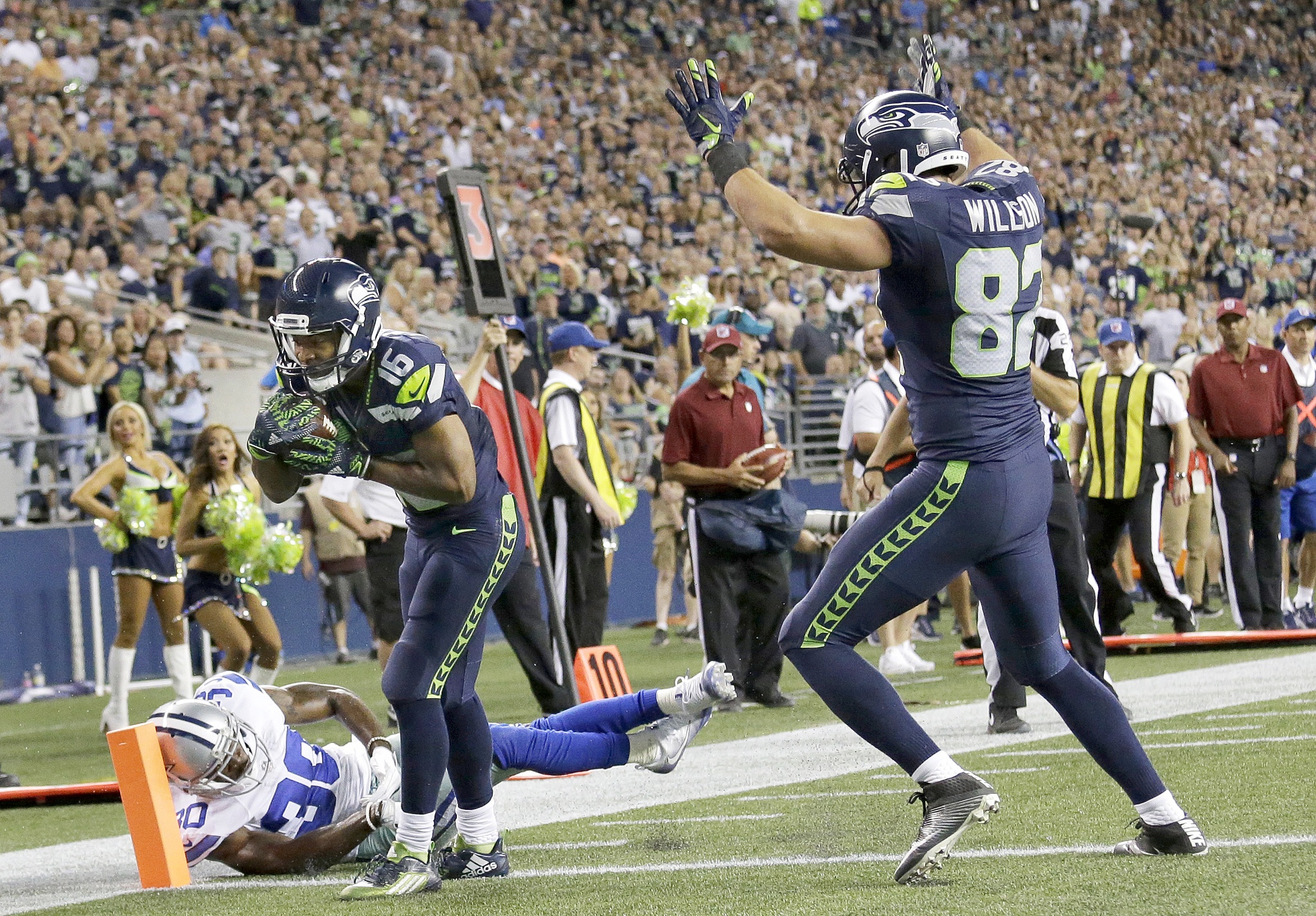 The Associated Press                                Seattle’s Tyler Lockett (16) scores a touchdown past Dallas’ Anthony Brown, left, as Seahawks tight end Luke Willson signals the score during a preseason game.