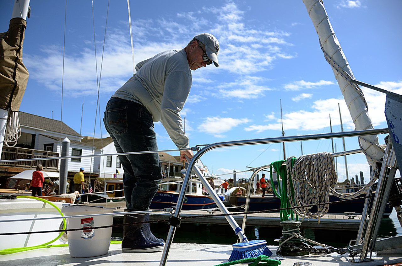 Dan Parnel of Auburn swabs the deck of his boat the Susan Joanne in preparation for the week’s Wooden Boat Festival in Port Townsend. (Cydney McFarland/Peninsula Daily News)