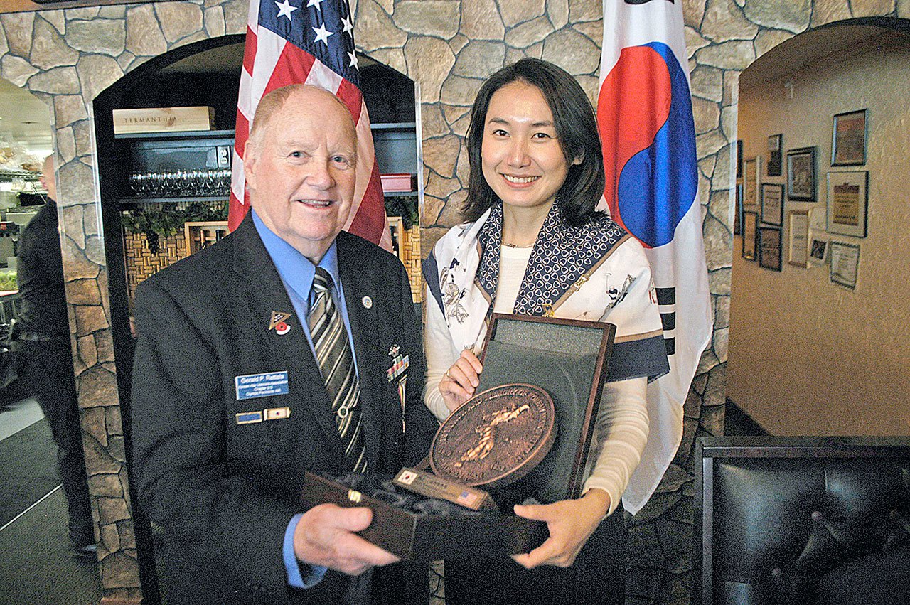 NaHye Kwon, representing the Consulate General of the Republic of South Korea in Seattle, presents a plaque commemorating the service of Americans during the Korean War to Gerald Rettela, Korean War Veterans Association Chapter 310 president in Port Angeles. (Chris McDaniel/Peninsula Daily News)