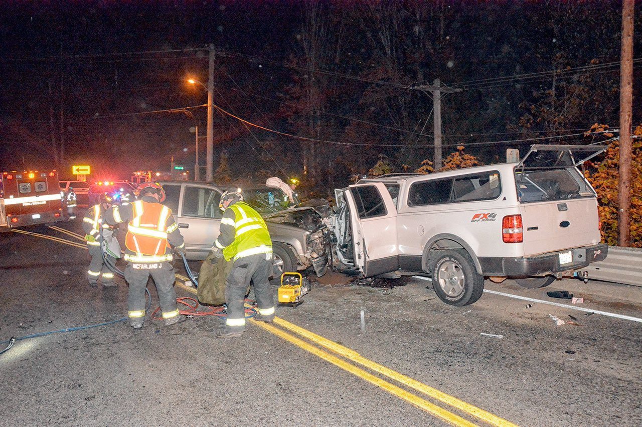 Personnel from Clallam Fire District No. 2 clean up following a two-vehicle head-on collision near the east end of the Elwha River Bridge on U.S. Highway 101 at 8:30 p.m. Friday. (Jay Cline/Clallam Fire District No.2)