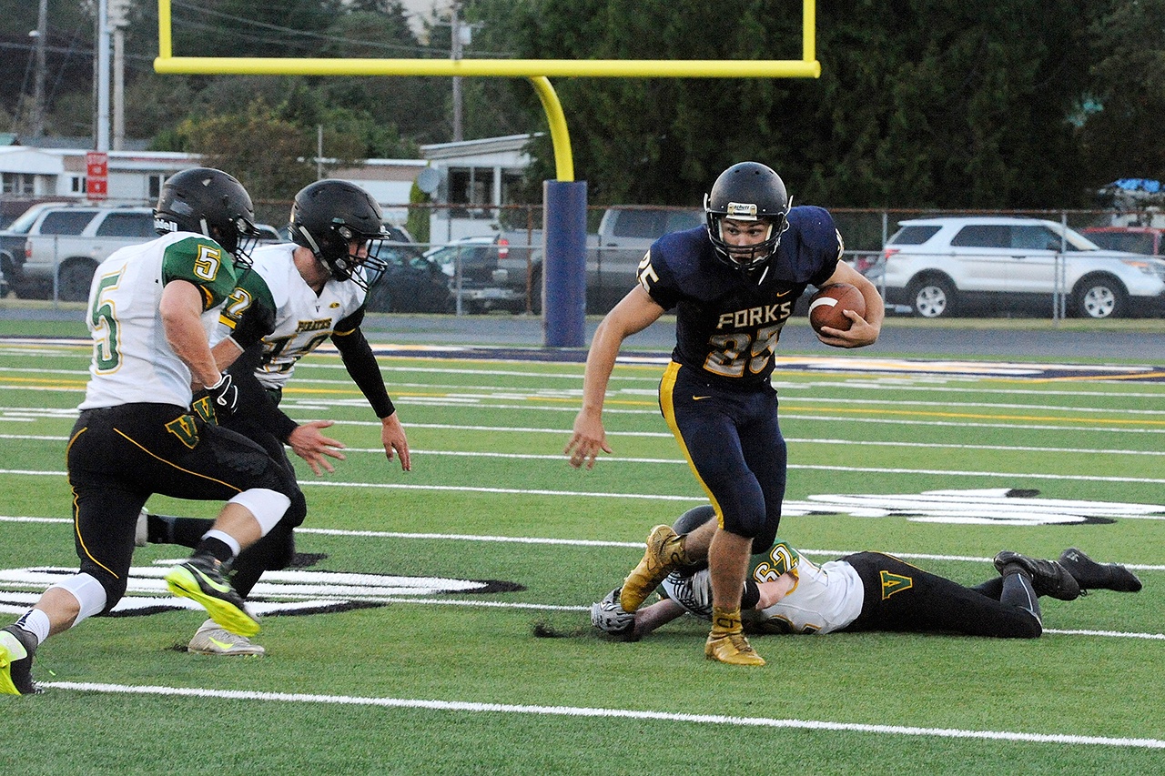 Lonnie Archibald/for Peninsula Daily News Forks running back Kenny Gale heads upfield after shaking off an ankle tackle during the Spartans&rsquo; season-opening win against Vashon.