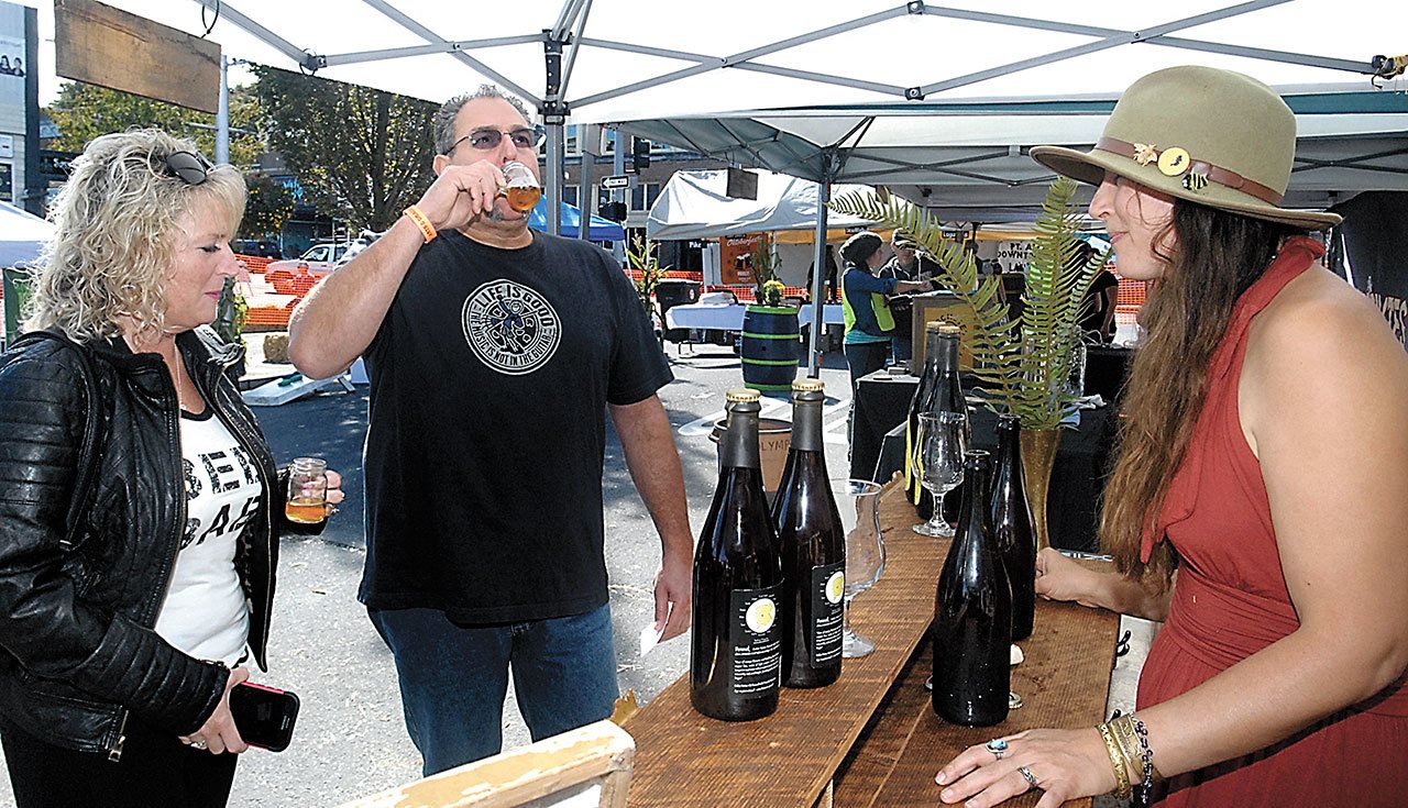 Shelly and John Barone of Port Angeles drink samples of beer served by Piper Corbett of the Port Townsend-based Propolis Brewing during the Arts & Draughts festival of beer, wine, cider, arts and music in downtown Port Angeles last year. (Keith Thorpe/Peninsula Daily News)