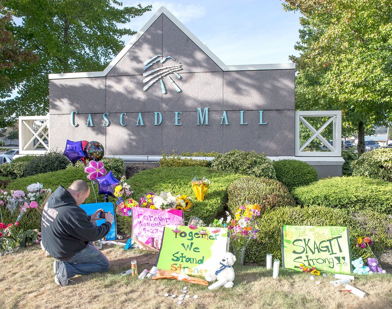 Chris Nelson of Burlington takes a picture of a memorial in Burlington to five victims killed in a shooting on Friday at Cascade Mall. (The Associated Press)