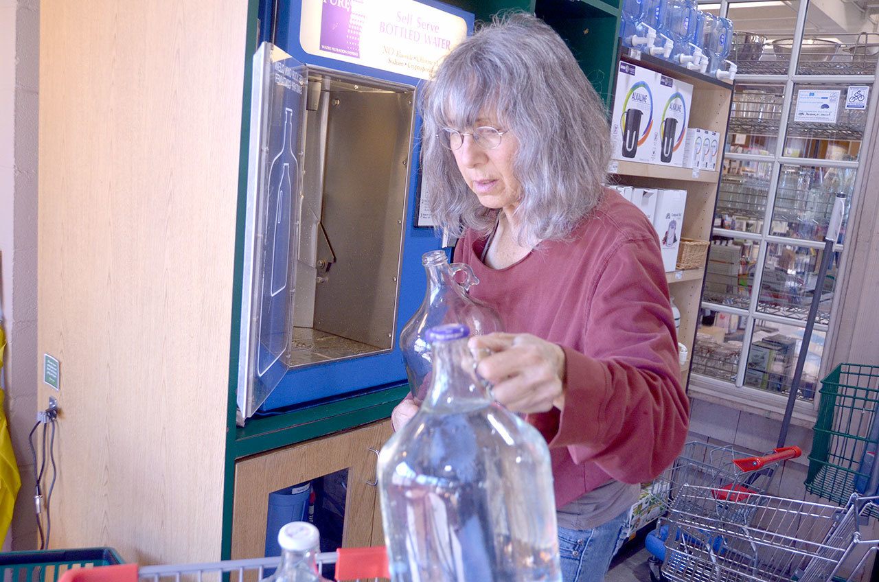 Roslyn Stevens of Chimacum fills bottles at the self serve bottled water station at the Port Townsend Co-Op. Port Townsend’s water has been deemed safe to drink, but Stevens and many others choose the bottled option since it’s free of the chemicals like chlorine that are used to purify local drinking water. (Cydney McFarland/Peninsula Daily News)