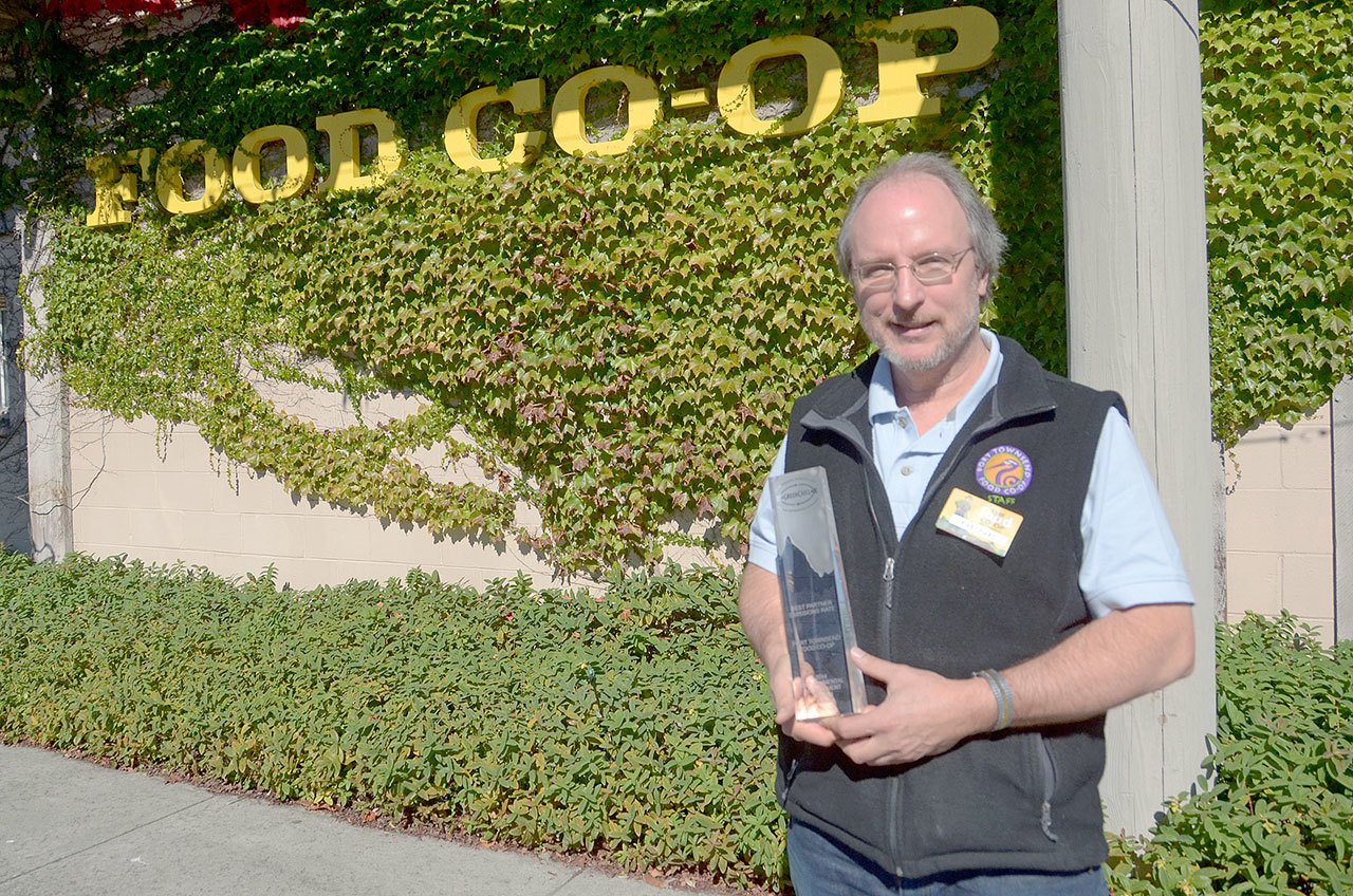 Port Townsend Co-op facilities manager Rene Tanner stands in front of the co-op with last year’s trophy from the EPA GreenChill program. The co-op has been awarded two years in a row for its efforts in lowering its refrigerant emissions. (Cydney McFarland/Peninsula Daily News)