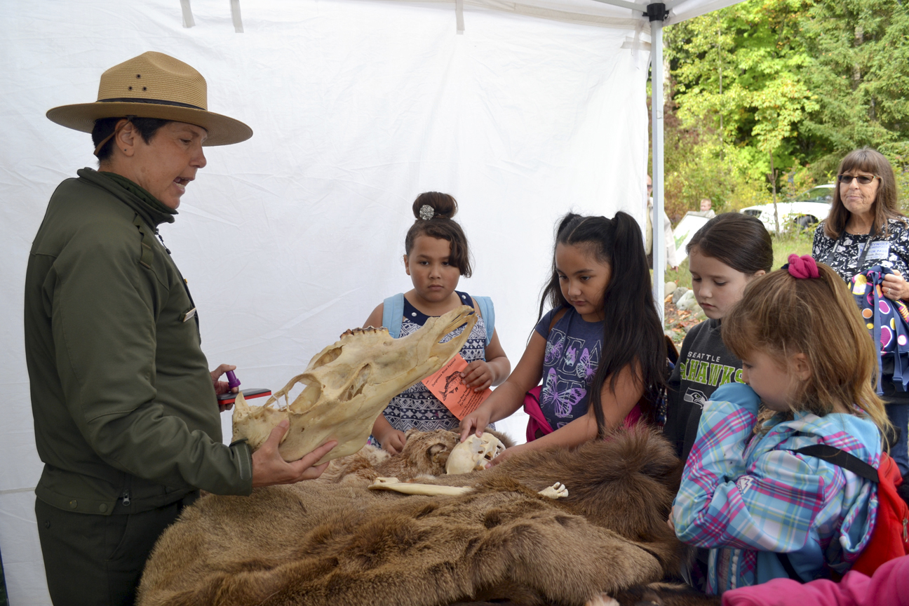 Olympic National Park Ranger Theresa Ferraro talks with Greywolf Elementary School students, from left, Kiana Redner, Emma Vose, Rylie Doig and Taylor Bugge from Shannon Green and Sheri Burke’s third-grade class about animals at the Dungeness River Festival. (Matthew Nash/Olympic Peninsula News Group)