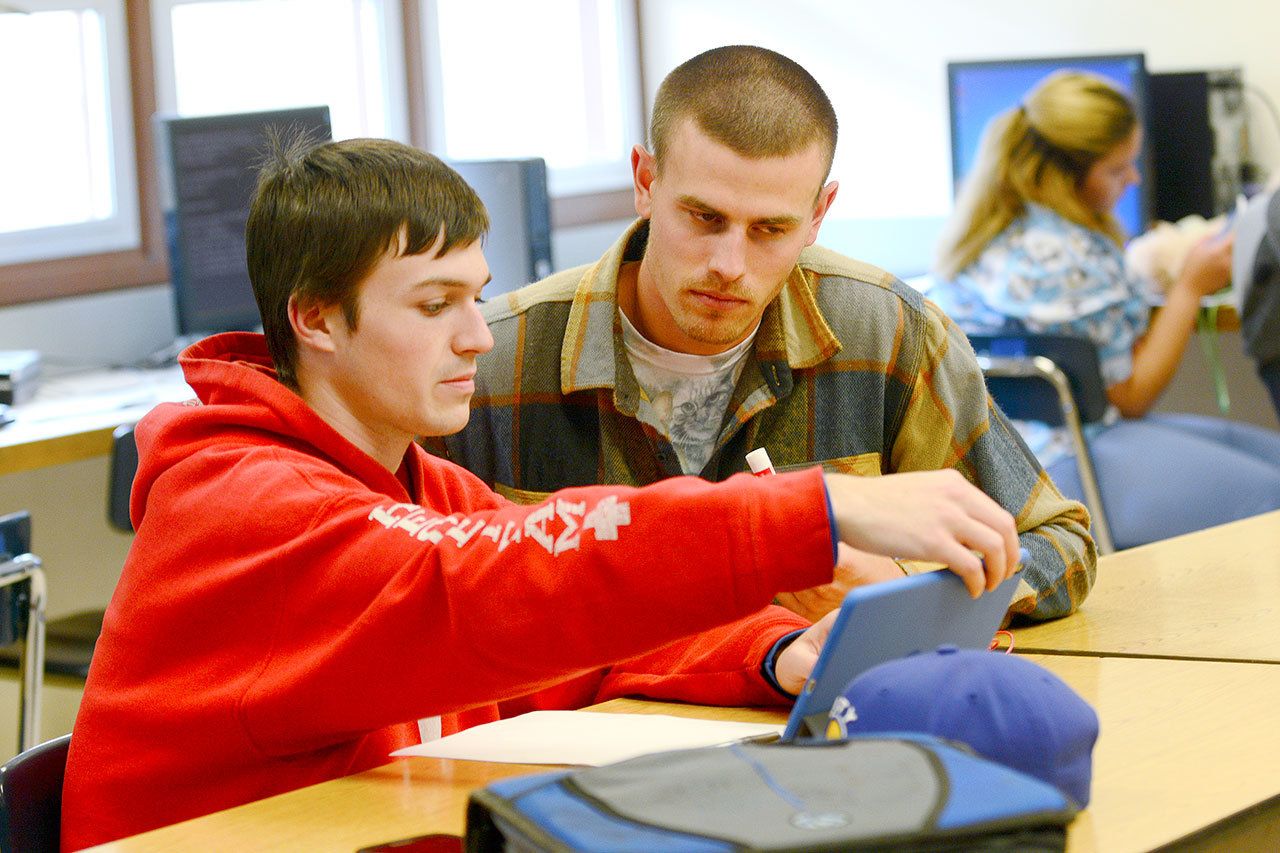 Crescent High School science and year book teacher Brad Ahrndt works with senior Austin Hedger-Irvins on Monday. Crescent High School was recently recognized as a school of distinction. (Jesse Major/Peninsula Daily News)