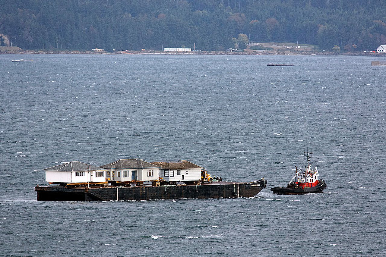 A tug towing a barge loaded with three houses anchors off Naval Magazine Indian Island in the south end of Port Townsend Bay on Tuesday evening. (Steve Mullensky/for Peninsula Daily News)