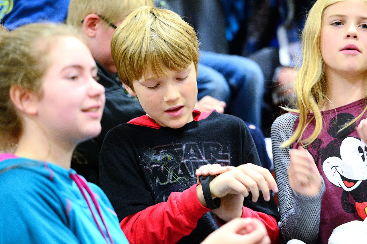 Andrew Halberg, a 10-year-old fifth-grade student at Roosevelt Elementary School, checks out his new Sqord, a device similar to Fitbit, during a kick-off event Monday. (Jesse Major/Peninsula Daily News)