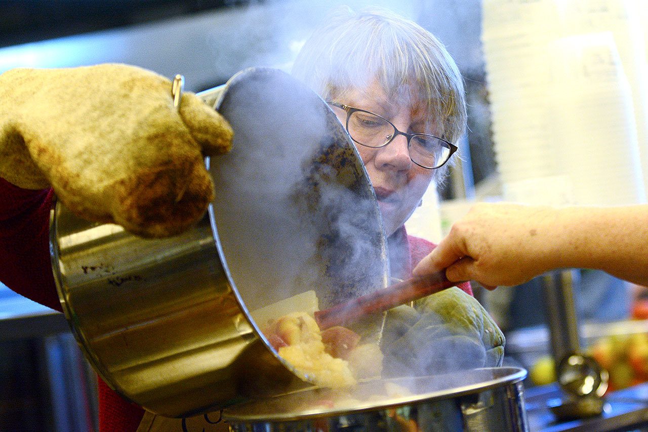 Patty Lebowitz pours cooked apples into a food mill as volunteers with the Washington State University Clallam County Extension Office turned 1,500 pounds of apples into applesauce Tuesday to be distributed in the county. (Jesse Major/Peninsula Daily News)