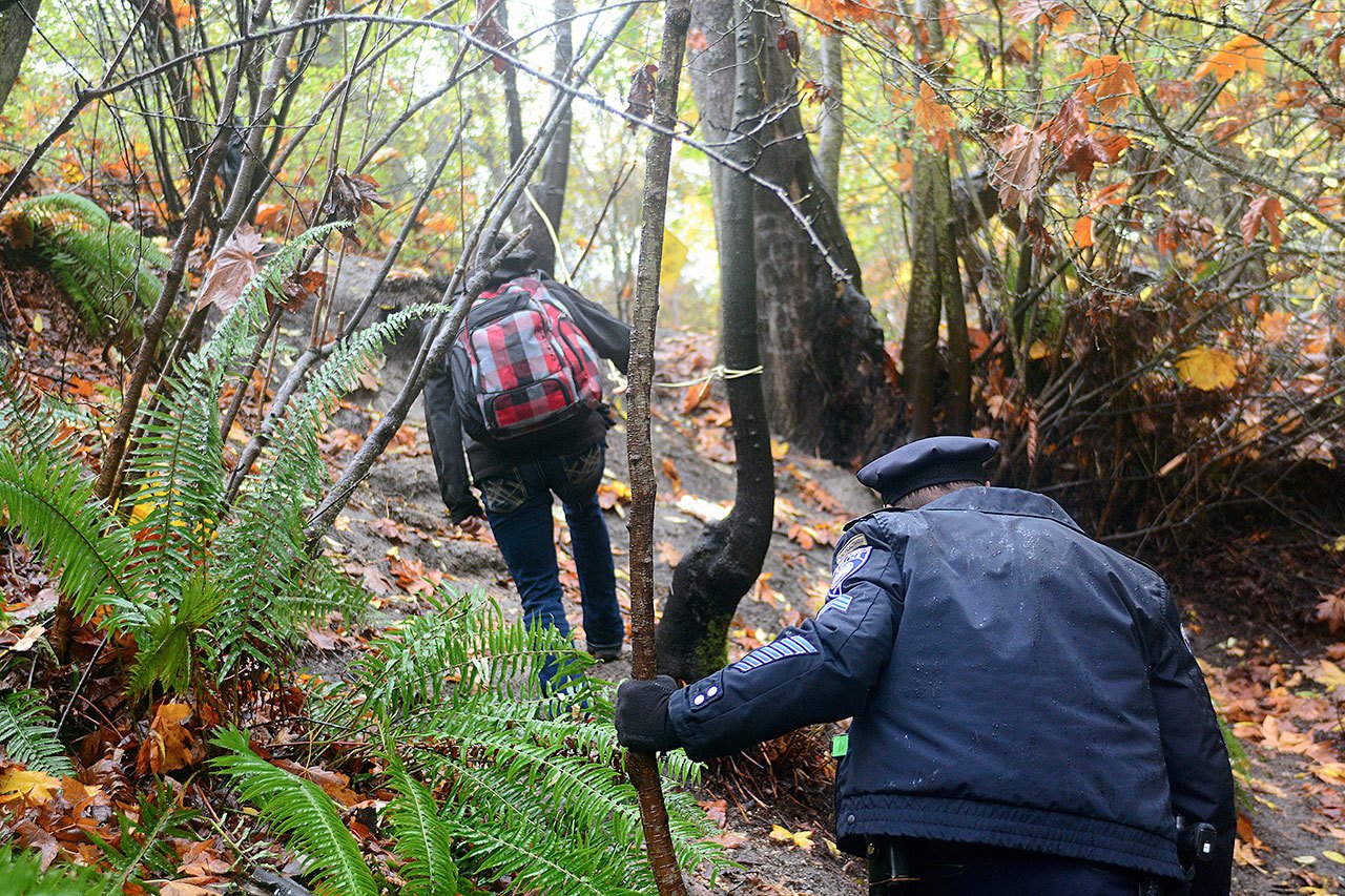 Viola Ware, program director of coordinated intake for Serenity House, and Sgt. Jason Viada of the Port Angeles Police Department walk out of a homeless camp in Port Angeles while looking for people who would benefit from Serenity House’s services. (Jesse Major/Peninsula Daily News)