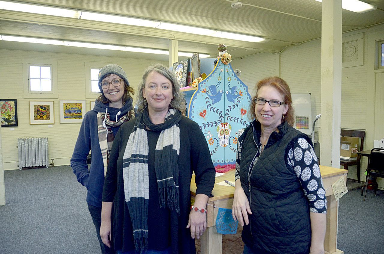 Artists Julie Read, left, and Lucie Duclos, right, along with Port Townsend School of the Arts program and operations manager Holly Green stand in front of the community Day of the Dead altar at the school in Fort Worden. (Cydney McFarland/Peninsula Daily News)
