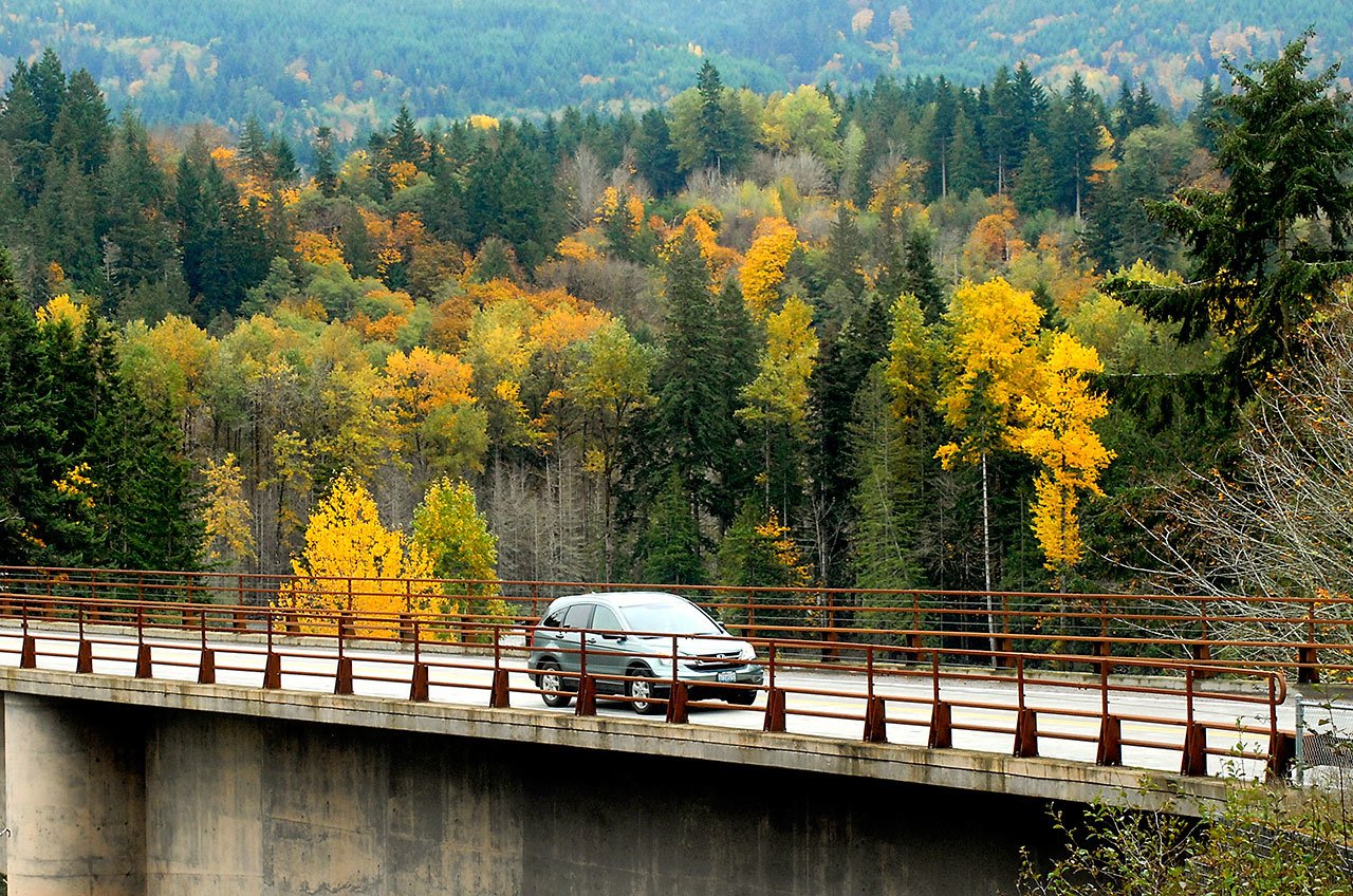 A vehicle makes its way over the Elwha River Bridge west of Port Angeles against a backdrop of trees in their full autumn colors. (Keith Thorpe/Peninsula Daily News)