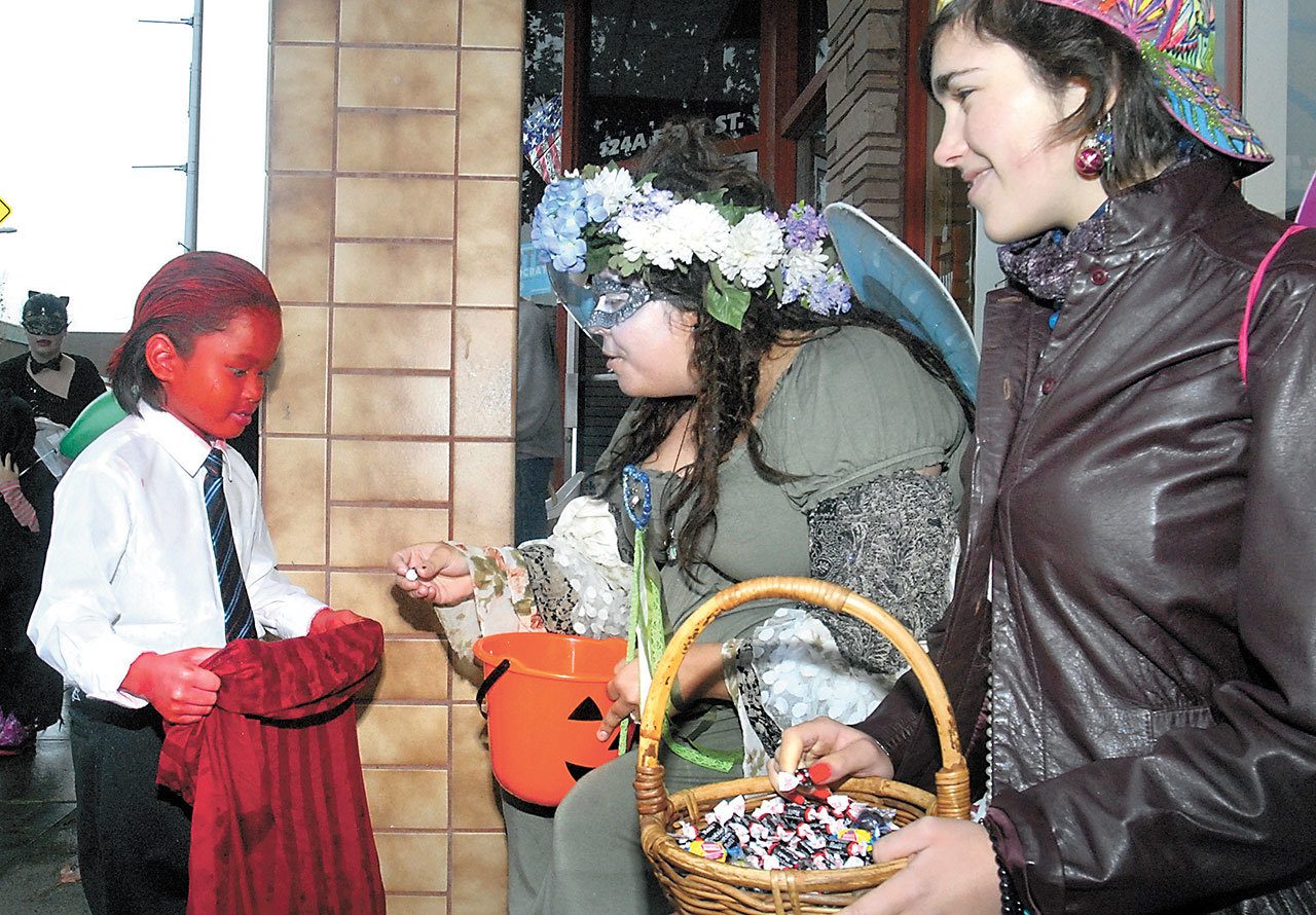 Eight-year-old Hayden Hull of Port Angeles, left, receives candy from Izzy Gray, center, and Jena Klein in front of the InSpired! gift store during Halloween festivities in downtown Port Angeles in 2015. (Keith Thorpe/Peninsula Daily News)