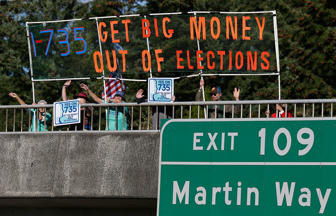 The Associated Press                                Supporters of Initiative 735 hold a banner above the Interstate 5 freeway during the evening commute in Lacey.