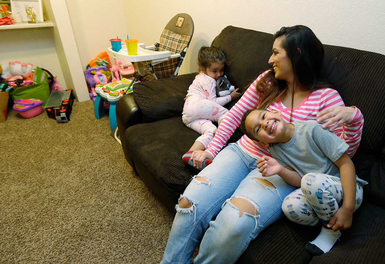 Danielle Mendoza helps two of her three children, Lola, 2 1/2, left, and Joseph, 5, get ready for bed in her apartment in Renton earlier this month. Mendoza, a cashier at a grocery store, is one of some 730,000 workers in Washington state who backers say would see their pay jump if voters approve Initiative 1433. (Ted S. Warren/The Associated Press)
