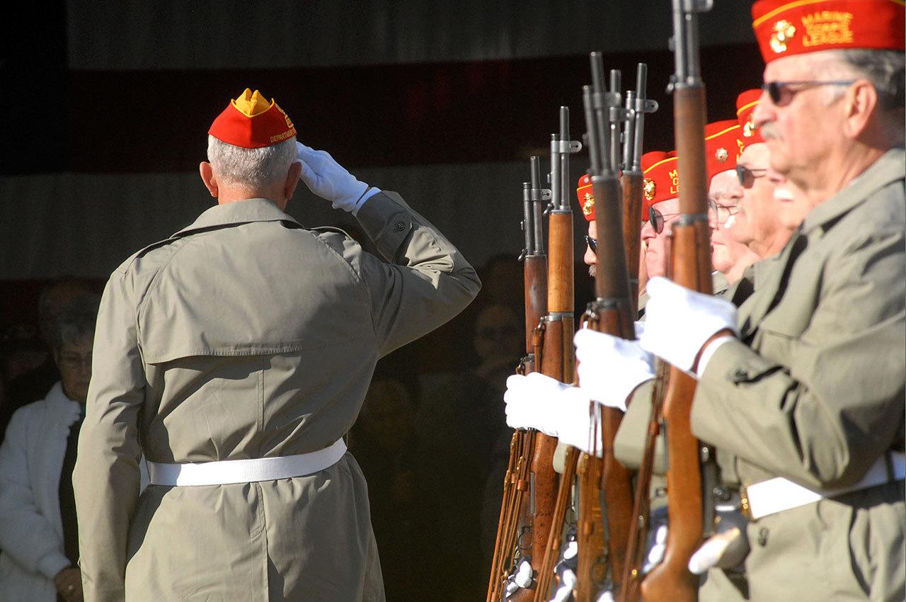 Mark Schildknecht, left, salutes into the aviation hangar after leading a three-volley rifle salute conducted by Mount Olympus Detachment 897 of the Marine Corps League on Veterans Day last year. (Keith Thorpe/Peninsula Daily News)