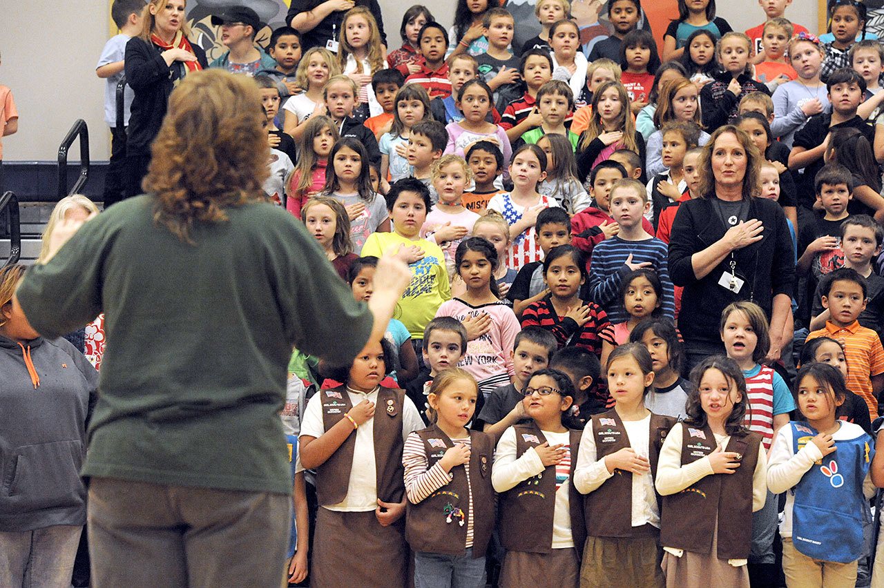 Band director Rebecca Murillo leads Brownies and Forks Elementary School students through patriot songs during the all-school Veterans Day assembly Thursday in the Forks High School gym. Veterans as well as the public were invited to the assembly composed of the Forks school band, various speakers, Forks Girl Scouts and Forks school faculty. (Lonnie Archibald/for Peninsula Daily News)