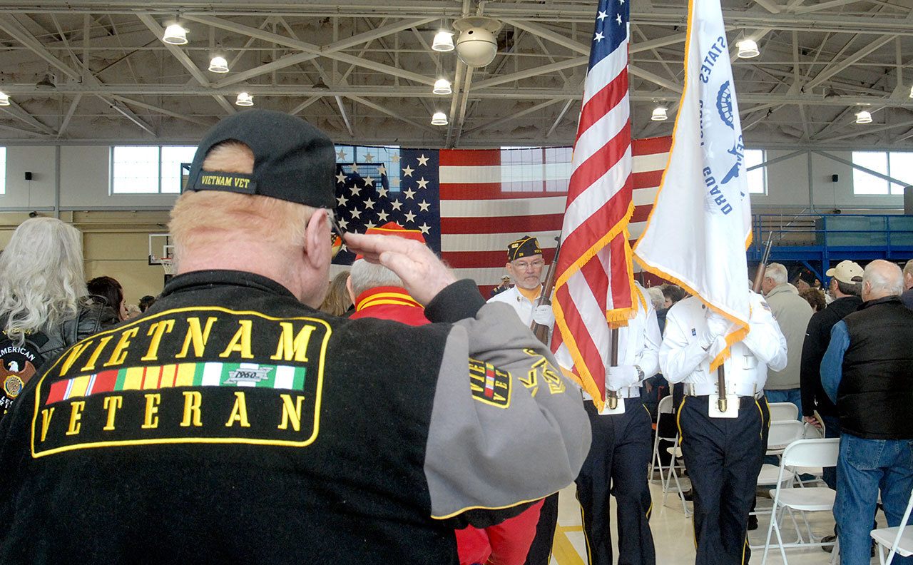 Mike Money of Port Angeles, a U.S. Navy veteran who served in Vietnam, salutes as a color guard passes during Friday’s Veterans Day ceremony in the hangar of U.S. Coast Guard Air Station/Sector Field Office Port Angeles. (Keith Thorpe/Peninsula Daily News)
