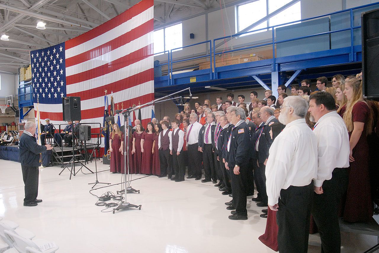 A combined chorus consisting of members of the Olympic Peninsula Men’s Chorus, the Grand Olympics Chorus of Sweet Adeline’s International, Mix Up A Capella and the Sequim High School Select Choir perform under the direction of Jim Davis during Friday’s Veterans Day ceremony in the hangar of U.S. Coast Guard Air Station/Sector Field Office Port Angeles. (Keith Thorpe/Peninsula Daily News)