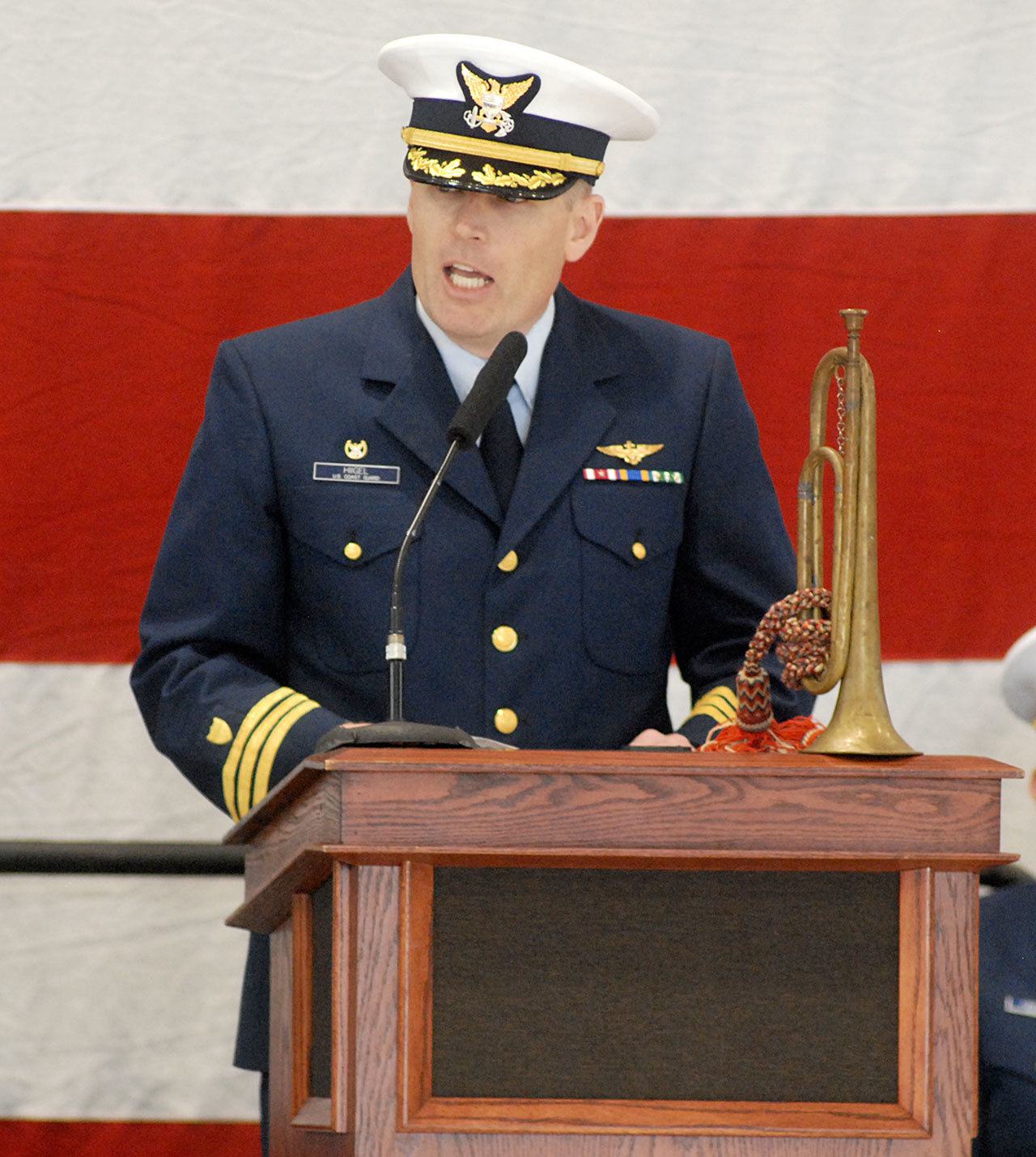 A family heirloom bugle graces the dais as U.S. Coast Guard Cmdr. Mark Hiigel, commanding officer of Air Station/Sector Field Office Port Angeles, speaks during Friday’s Veterans Day ceremony. (Keith Thorpe/Peninsula Daily News)