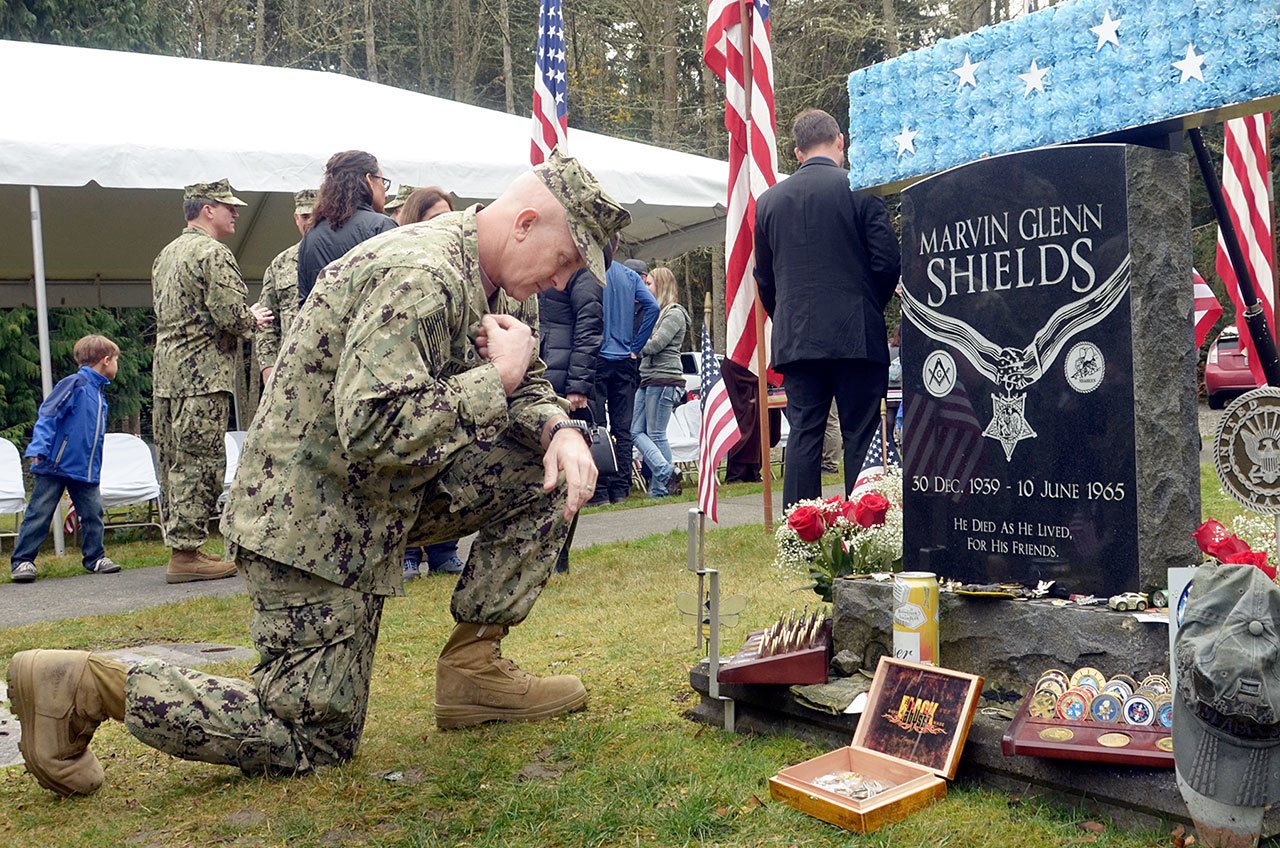 Capt. Christ Kurgan crosses himself beside the grave of Medal of Honor recipient Marvin Shields during the annual Veterans Day ceremony at the Gardiner Cemetery on Friday. (Cydney McFarland/Peninsula Daily News)