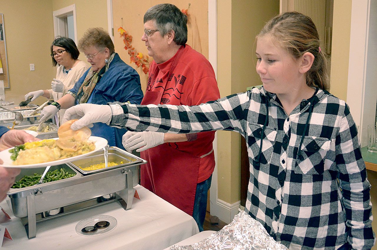 Ten-year-old Katherine Conlon hands out rolls at the Thanksgiving Eve meal at St. Paul’s Episcopal Church in Port Townsend. (Cydney McFarland/Peninsula Daily News)