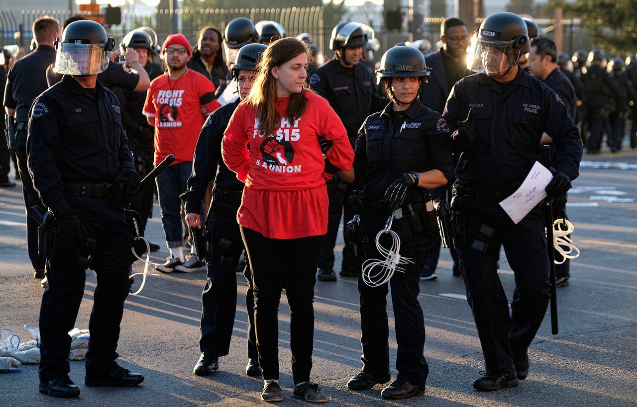 Protesters are arrested and taken into custody during a wage protest in downtown Los Angeles on Tuesday. A few dozen protesters blocked a downtown Los Angeles intersection as part of a national wave of demonstrations in support of higher wages and workers’ rights. (The Associated Press)