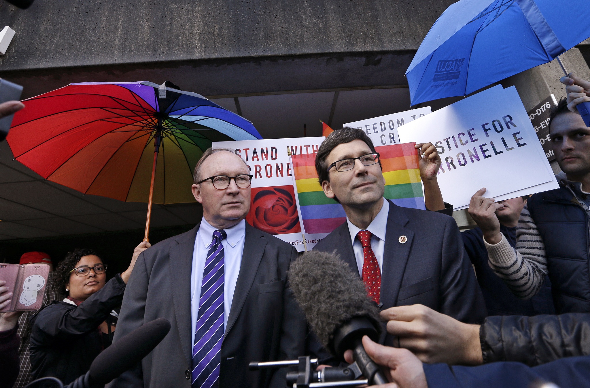 As supporters on both sides of the case vie for position behind, Attorney General Bob Ferguson, right, and ACLU attorney Michael Scott speak with reporters following a hearing Tuesday in Bellevue before Washington&rsquo;s Supreme Court about a florist who was sued for refusing to provide services for a same sex-wedding. (Elaine Thompson/The Associated Press)