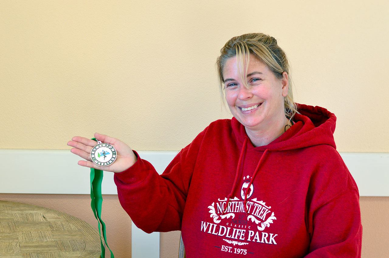 Stacy Eastman shows off the medal she won at the Bremerton Half Marathon. Olympic Community Action Programs has helped the Port Angeles woman as she strengthens her health. (Diane Urbani de la Paz/for Peninsula Daily News)
