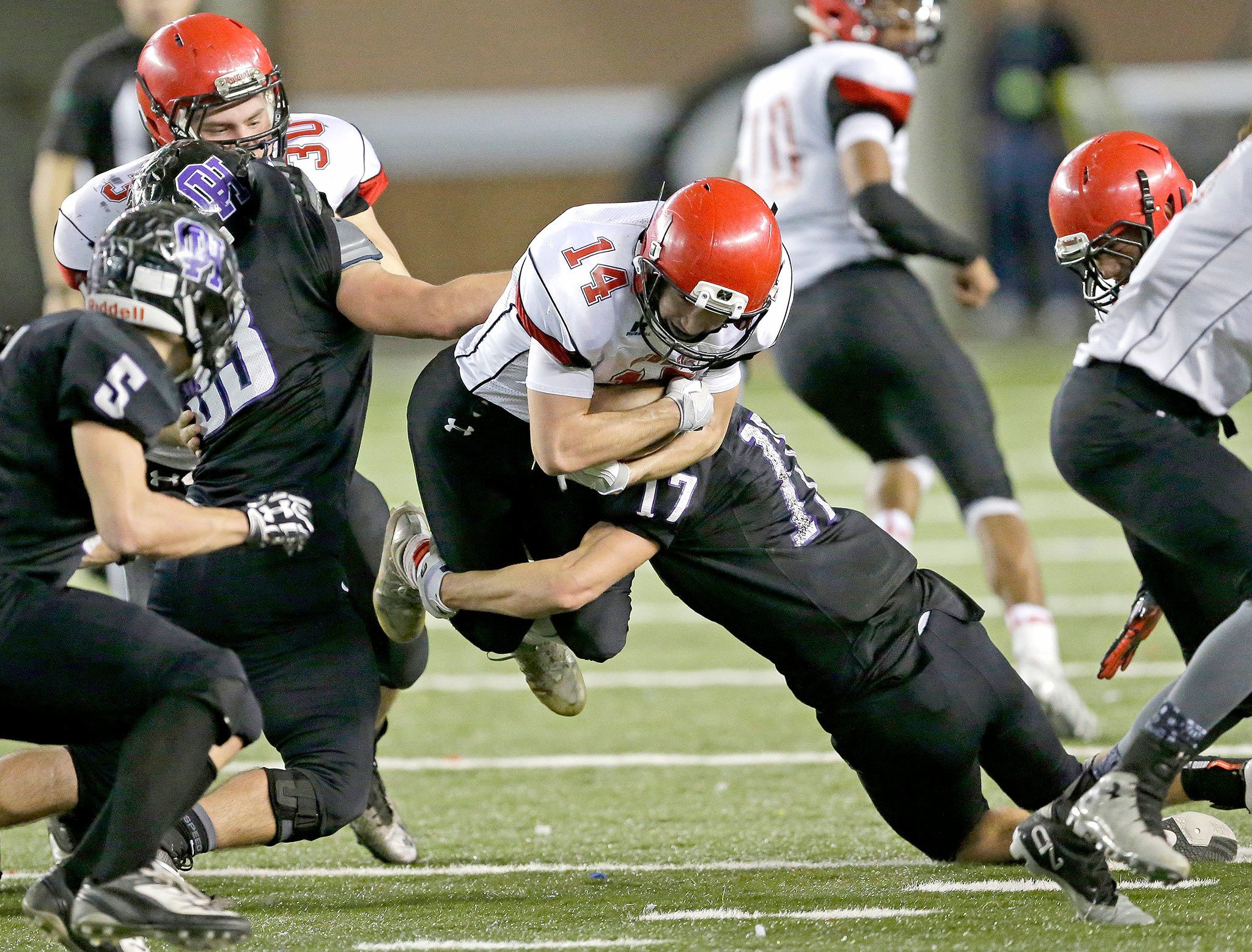 The Associated Press                                Neah Bay quarterback Cameron Buzzell (14) is tackled by Odessa-Harrington defensive linebacker John DeWulf (17) as he leaps for extra yardage in the first half of the Washington Div. 1B high school football championship Saturday at the Tacoma Dome.