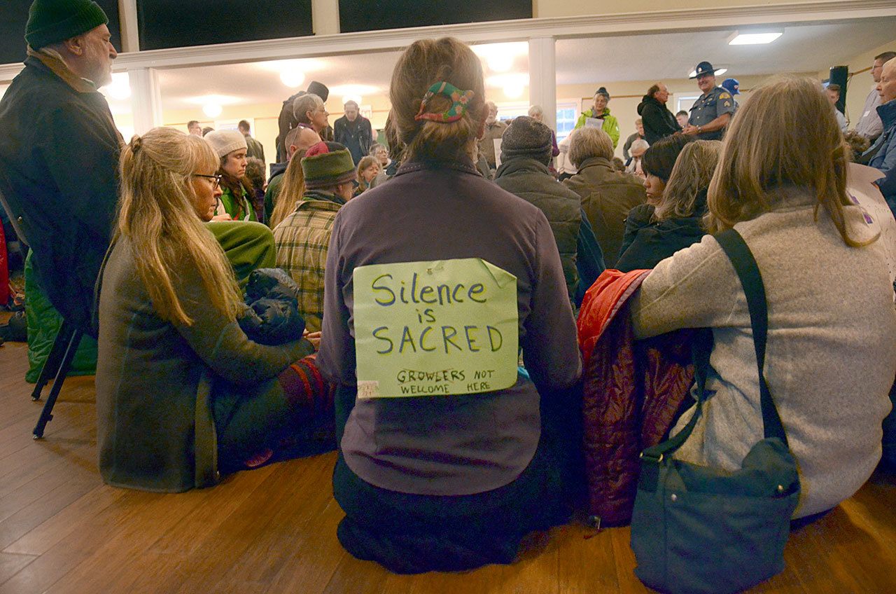 Protesters from Port Townsend and the surrounding areas participate in a silent sit-in at the Navy open house at Fort Worden on Monday. The group came to protest the Navy’s plan to add new Growler aircraft to training on Whidbey Island, creating more noise for surrounding communities. (Cydney McFarland/Peninsula Daily News)