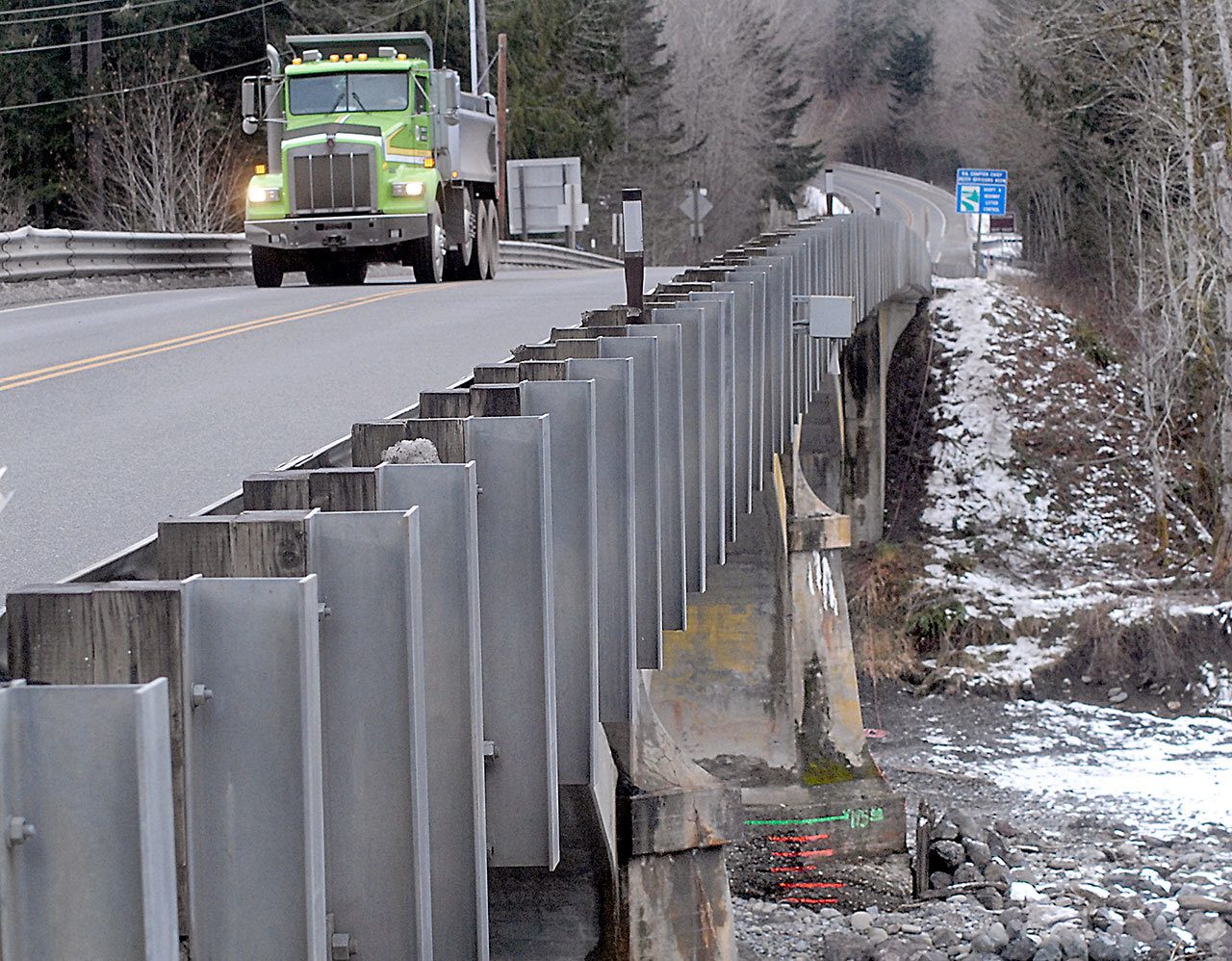 A dump truck crosses the Elwha River bridge Wednesday as markings on a bridge pier show the amount of scouring and erosion caused by the river. (Keith Thorpe/Peninsula Daily News)