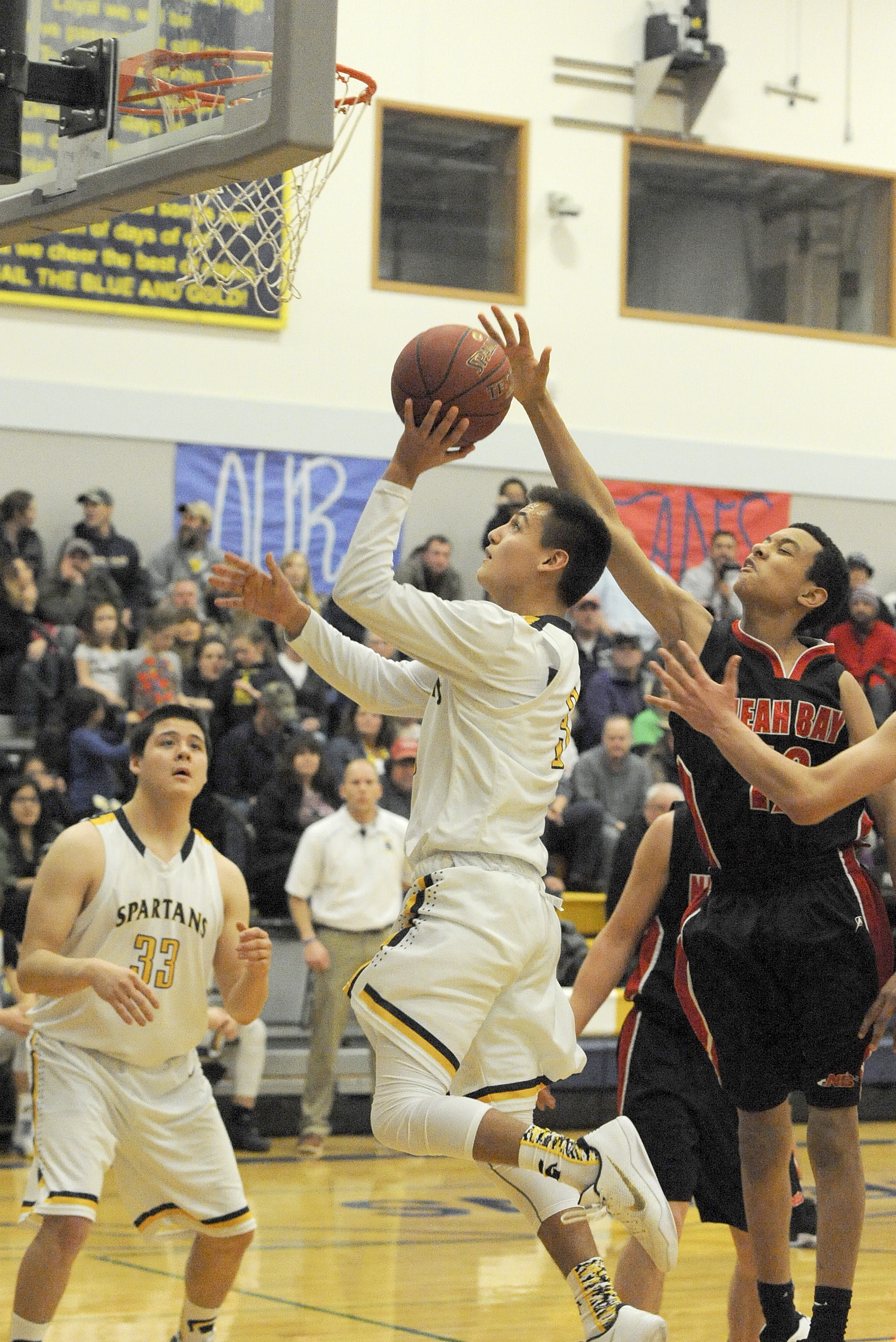 Lonnie Archibald/for Peninsula Daily News                                Forks’ Keishaun Ramsey shoots around the defense of Neah Bay’s Sean Bitegeko while the Spartans’ Austin Flores looks on. Forks won 77-50.