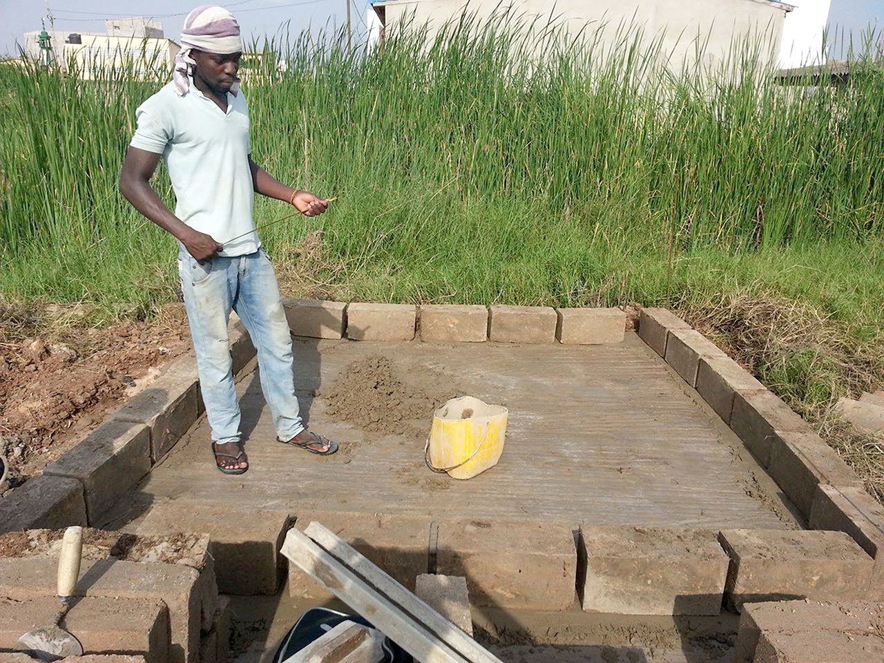 An unidentified man works on a compost toilet for a family living in the village of Zogbedgi, Togo, as part of the Dignity Toilets for Togo program. (Bedi Taouvik Boukari)